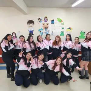 Grupo de amigas en un aula, vestidas con polerones negro y rosado, celebrando la amistad.