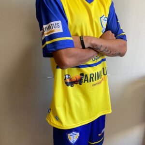 Joven atleta con uniforme amarillo y azul, listo para jugar al fútbol.