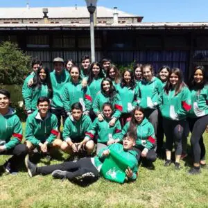 Estudiantes de 4to medio celebrando juntos en el exterior con polerones verdes.