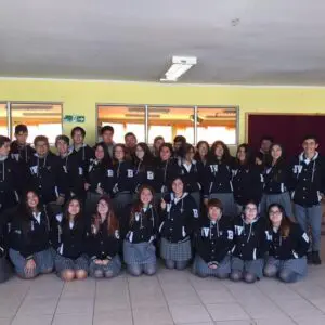 Estudiantes con polerones negros celebrando su curso en un ambiente escolar alegre.