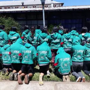 Jóvenes en polerones verdes, unidos en un evento cultural al aire libre.