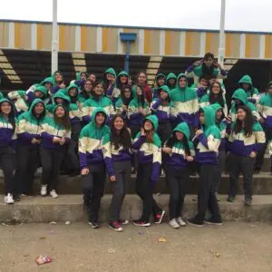 Grupo de adolescentes en polerones de colores celebrando la amistad en un ambiente alegre.