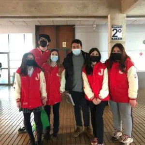 Estudiantes de 4to medio posando en el corredor escolar con polerones rojos y crema.