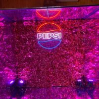 Cabina interactiva de Pepsi con luces neón y ambiente festivo para eventos.