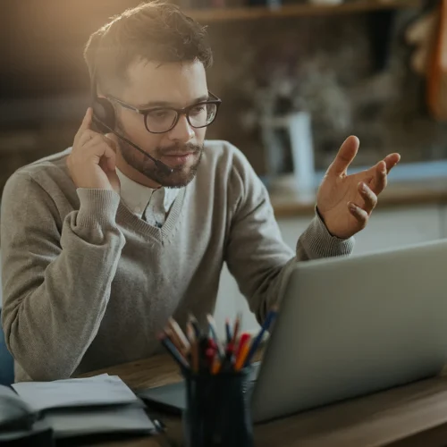 Joven profesional en reunión virtual, trabajando desde su acogedora oficina en casa.