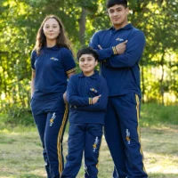 Tres jóvenes sonrientes en un entorno natural, vistiendo ropa deportiva azul y amarilla.