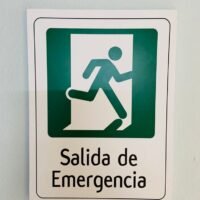 Señal clara de salida de emergencia con figura en movimiento y texto en español.