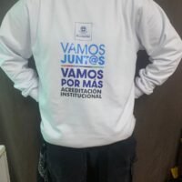 Sudadera blanca de equipo con mensaje motivacional sobre acreditación institucional.