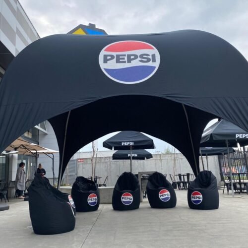 Toldo Pepsi y cómodos pufs para un evento promocional vibrante y acogedor.